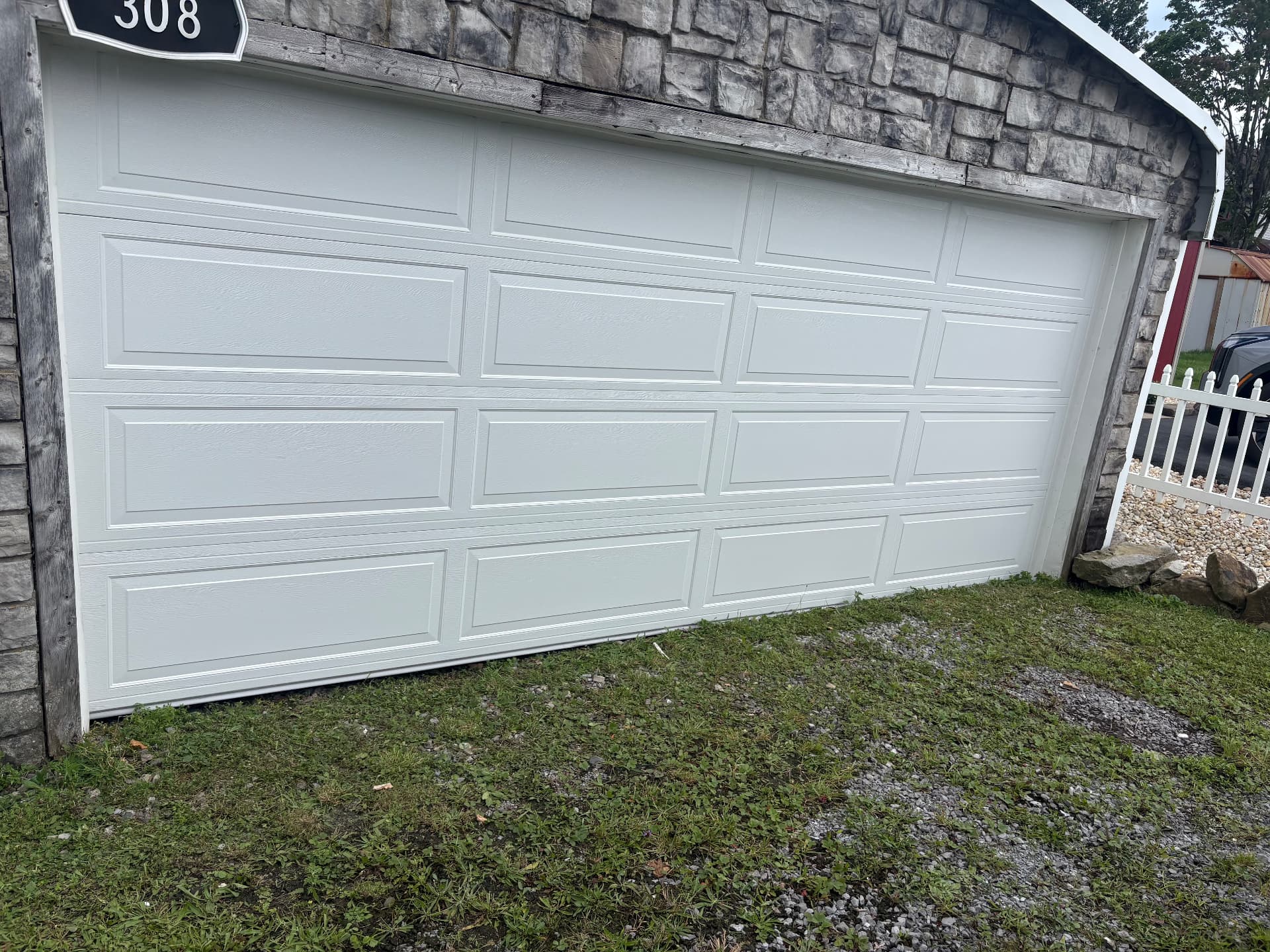 After: new white raised-panel garage door installed and sealed to the frame